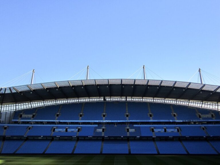 The Etihad Stadium, Manchester City's ground, seen from pitch level under a clear blue sky