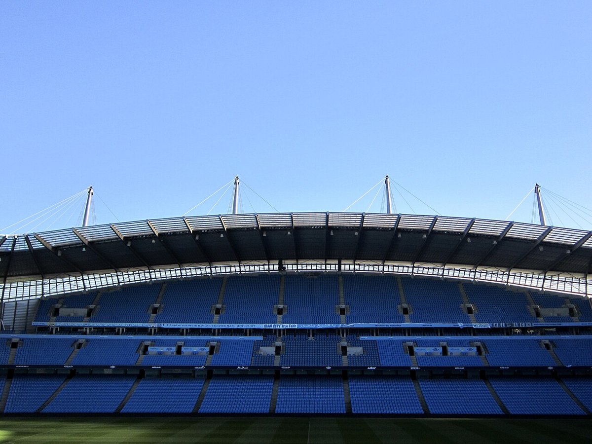 The Etihad Stadium, Manchester City's ground, seen from pitch level under a clear blue sky
